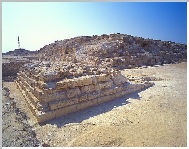 Ruins of the Djedefre Pyramid with weathered stone blocks under a clear blue sky.