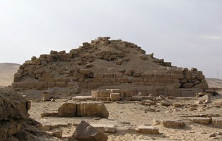 Ruins of a small stepped pyramid in an Egyptian desert site.