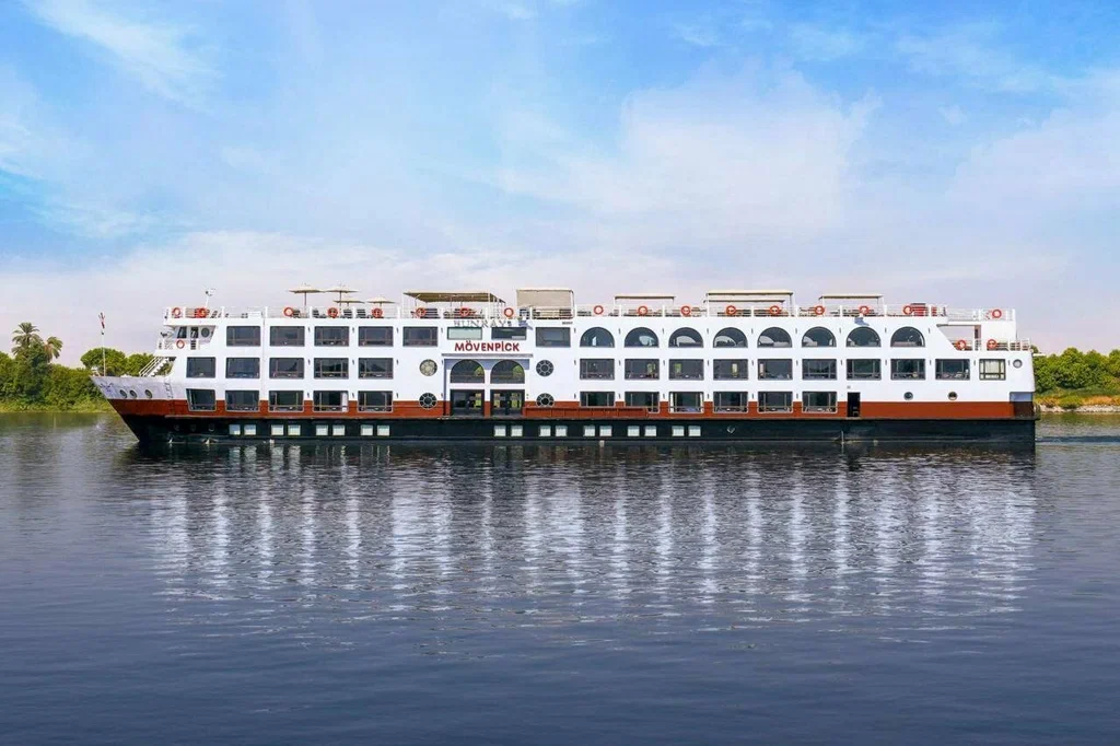 Mövenpick Nile cruise ship sailing along the Nile River in Egypt under a clear blue sky.