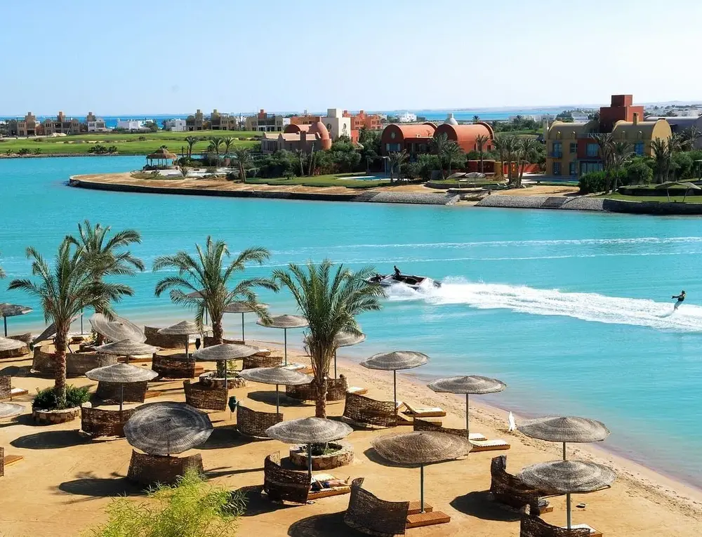 Red Sea beach in Egypt with palm trees, sun loungers, and turquoise water at a resort.